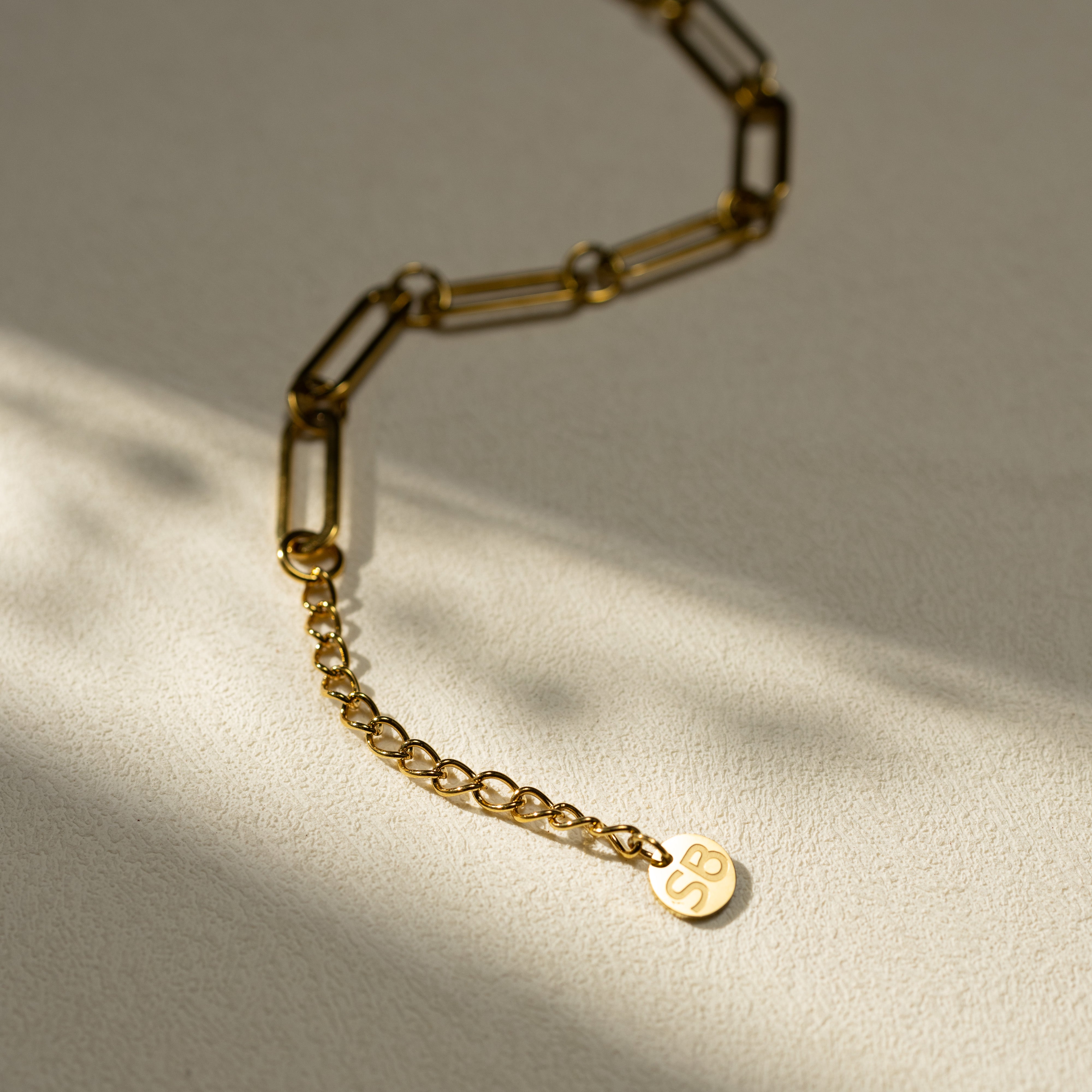 ISTP MBTI 18K gold paperclip chain necklace featuring the letter “S”, shown in a minimalist closeup on a textured neutral background.