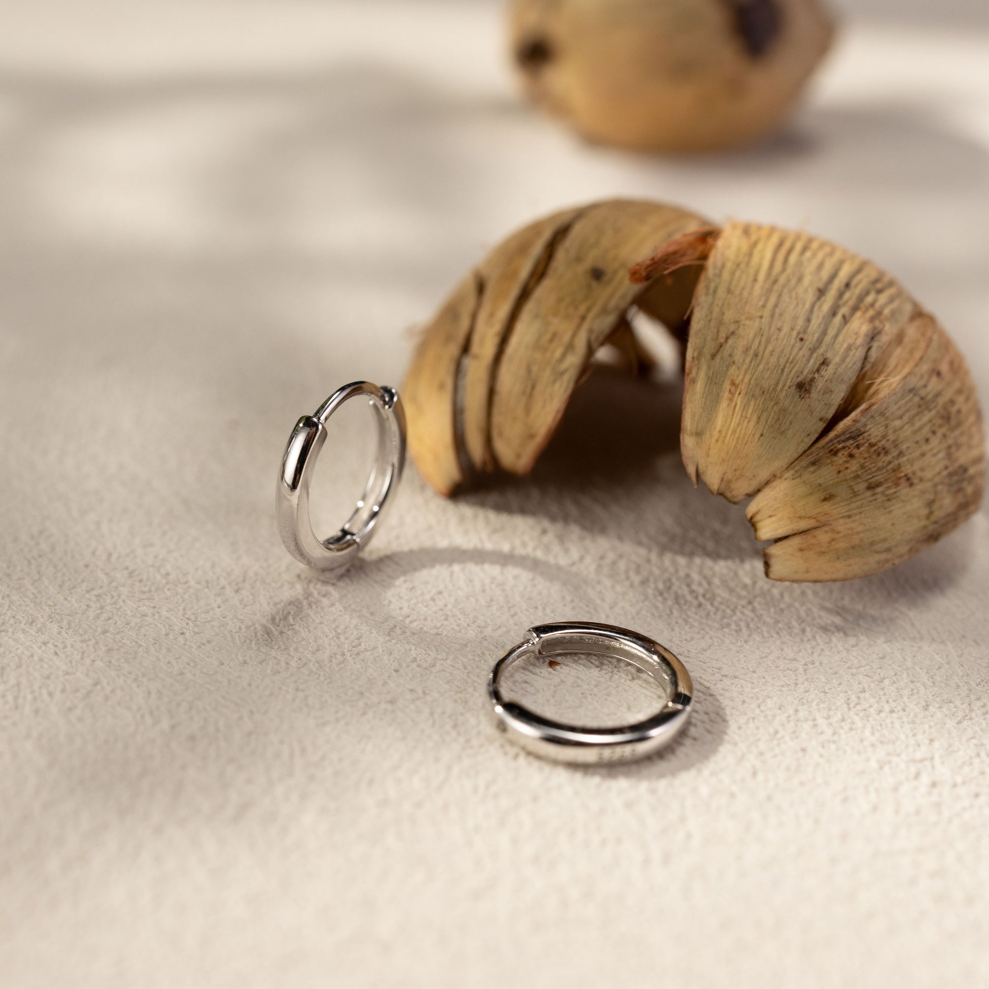 Lina smooth silver huggie earrings in a soft lifestyle scene with natural shadows, minimalist waterproof hypoallergenic everyday hoops by SILVBREEZE