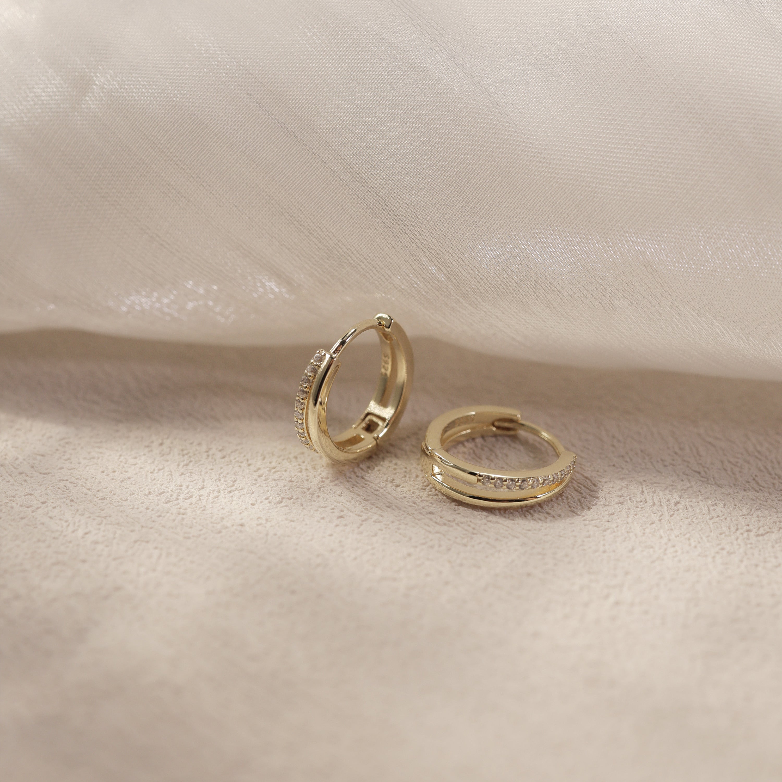 Nira gold vermeil huggie earrings with cubic zirconia in soft lifestyle scene, elegant waterproof everyday hoops by Silvbreeze