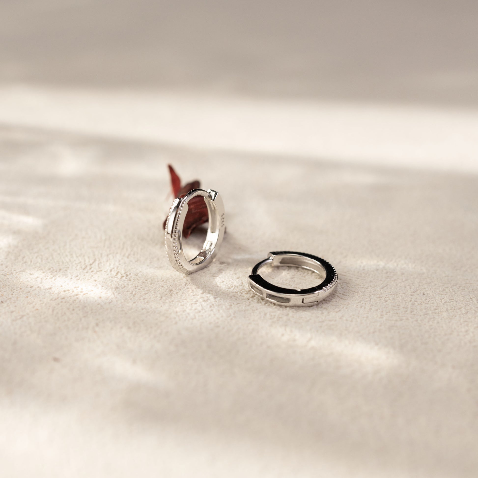 Onita white gold vermeil huggie earrings with detailed edge design, sterling silver lightweight hoops in natural lifestyle setting by SILVBREEZE