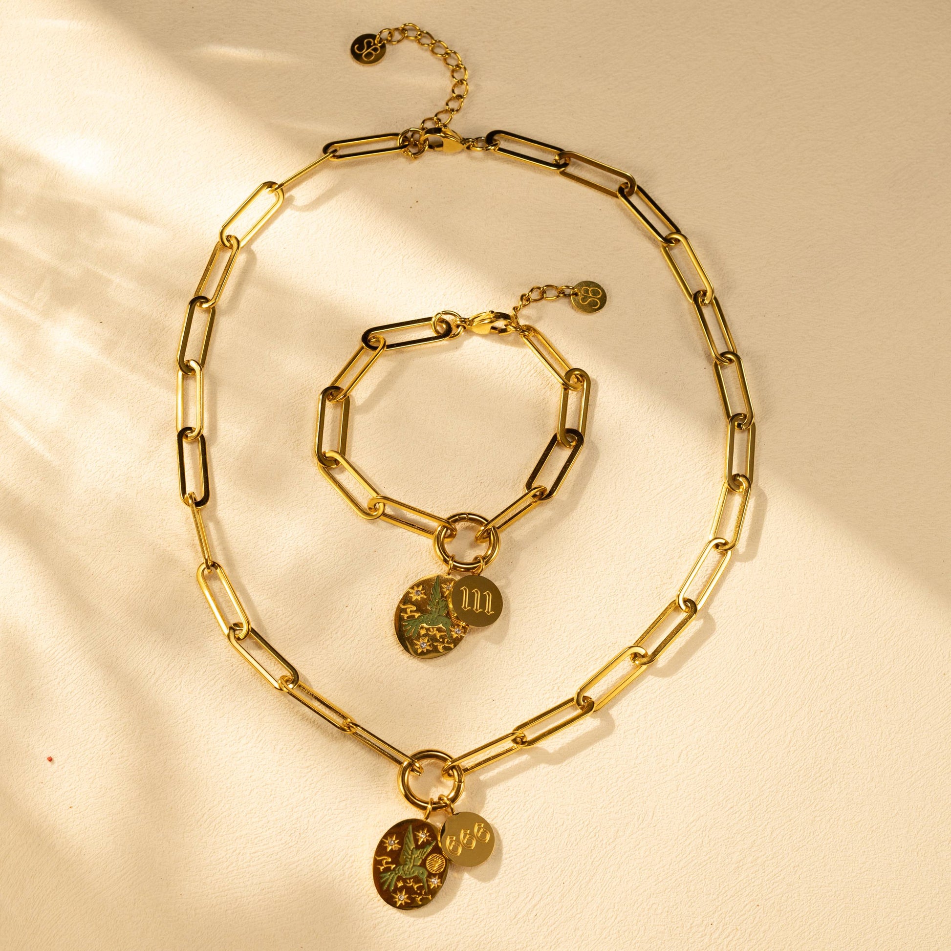 Silvbreeze Greenbird angel number 111 gold necklace and bracelet set displayed together in warm styled scene.
