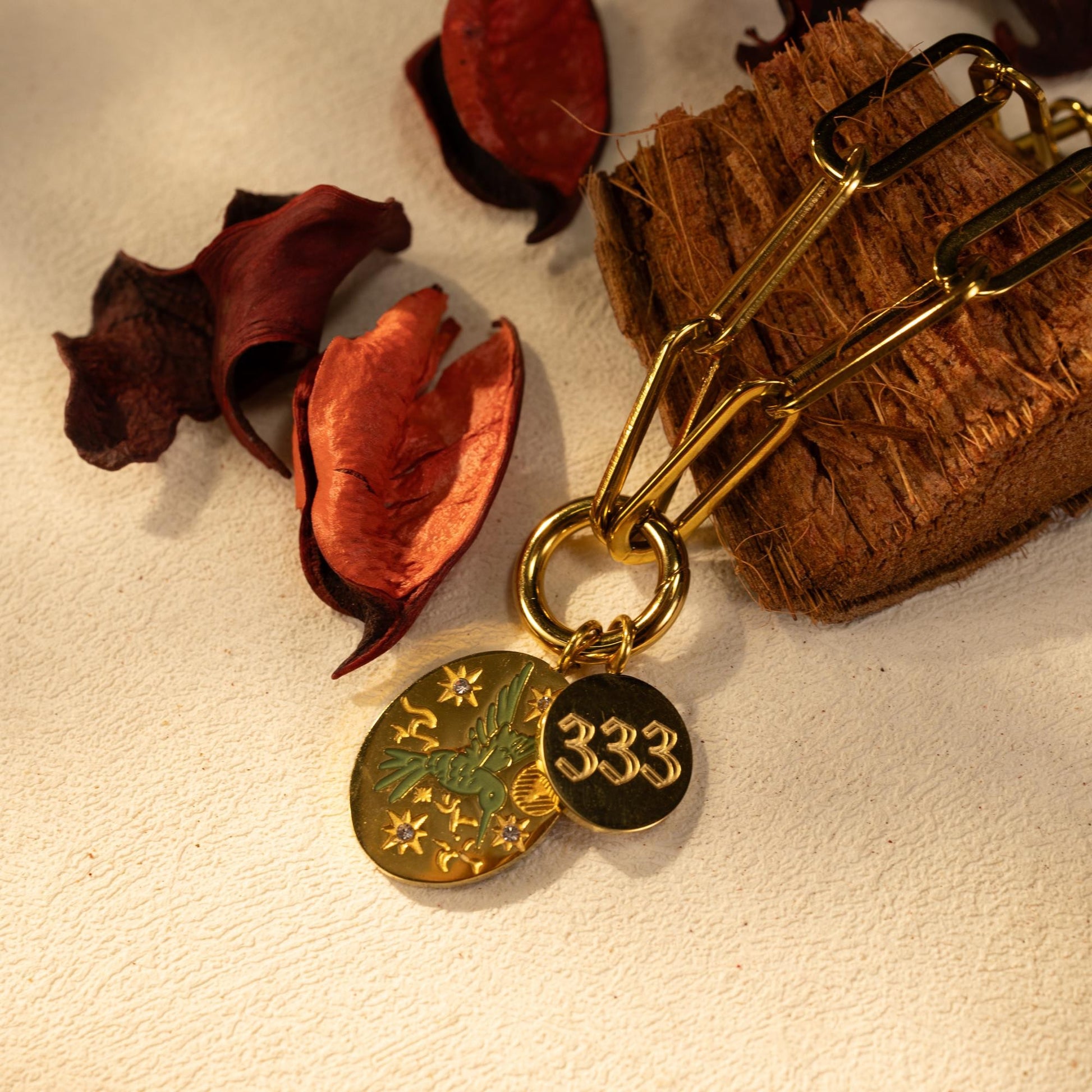 Close up of the Silvbreeze Zephyra Greenbird Angel Number Bracelet with 333 engraved charm on a gold paperclip chain.