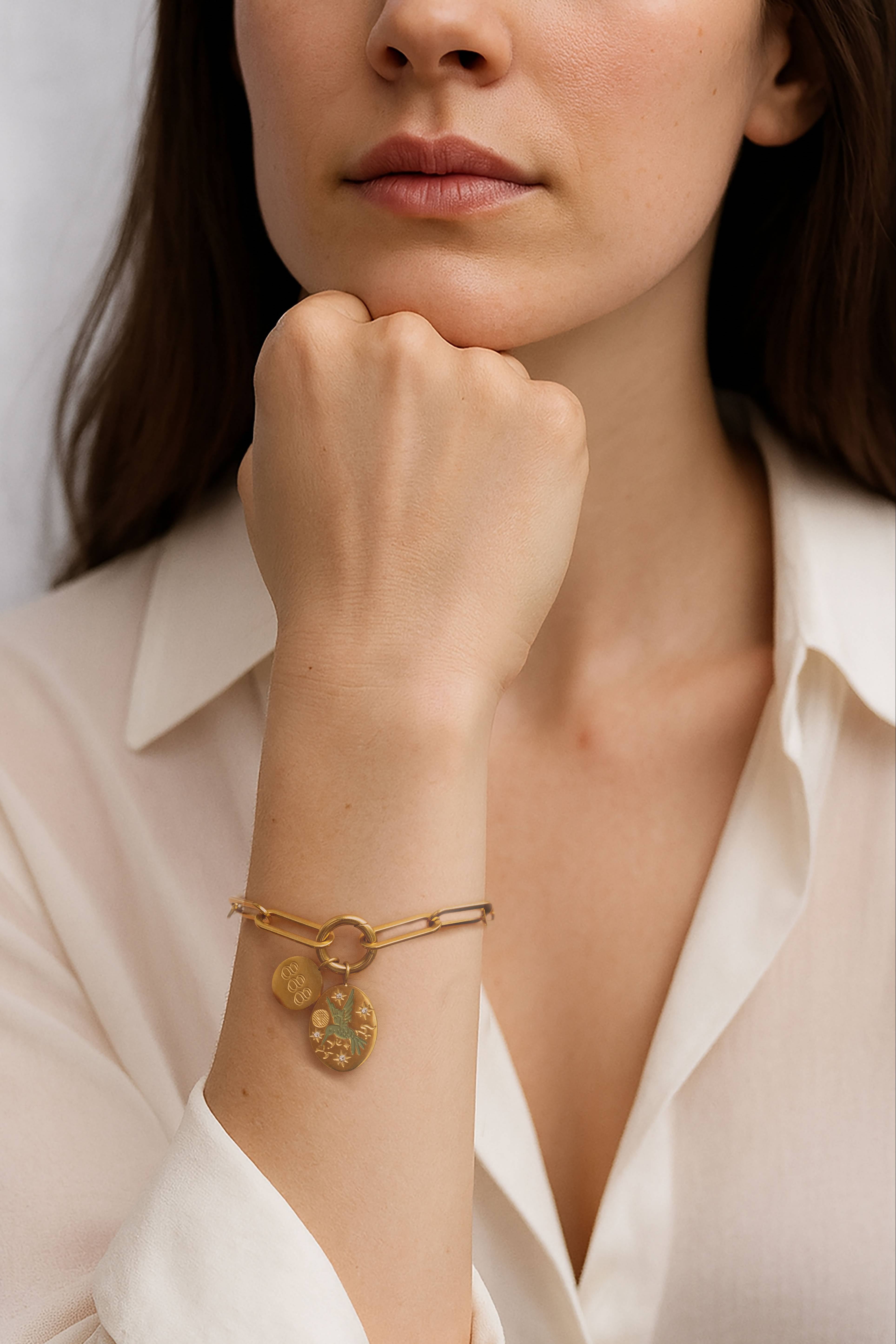 Model wearing the Silvbreeze Zephyra Greenbird Angel Number Bracelet, gold paperclip chain with engraved charms.
