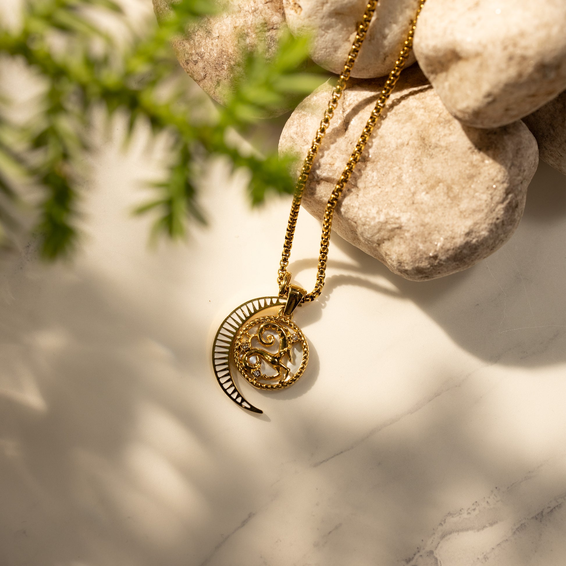 Silvbreeze Lunara Aries zodiac necklace with moon mother-of-pearl pendant on a round box chain, styled on natural stone background.