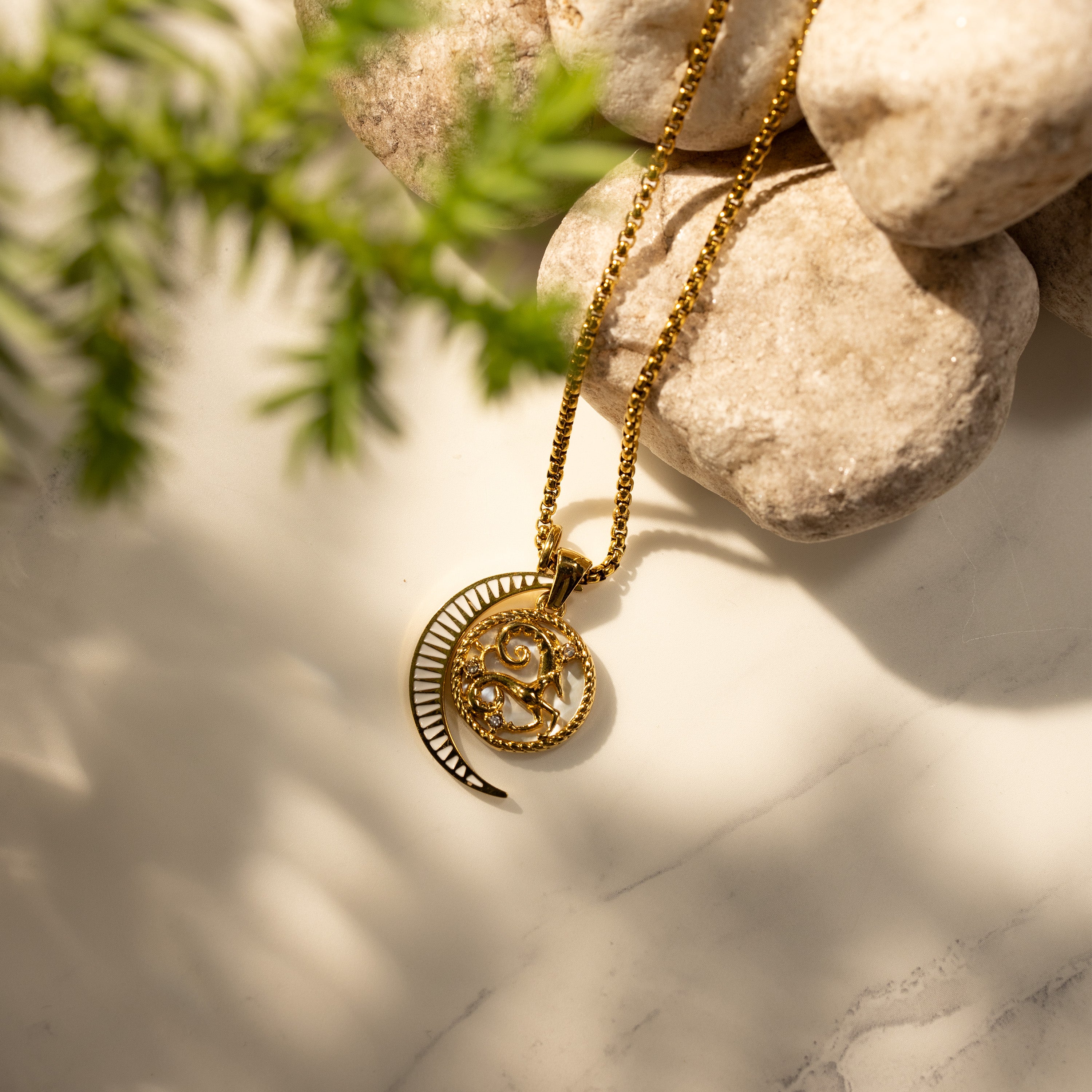 Silvbreeze Lunara Aries zodiac necklace with moon mother-of-pearl pendant on a round box chain, styled on natural stone background.