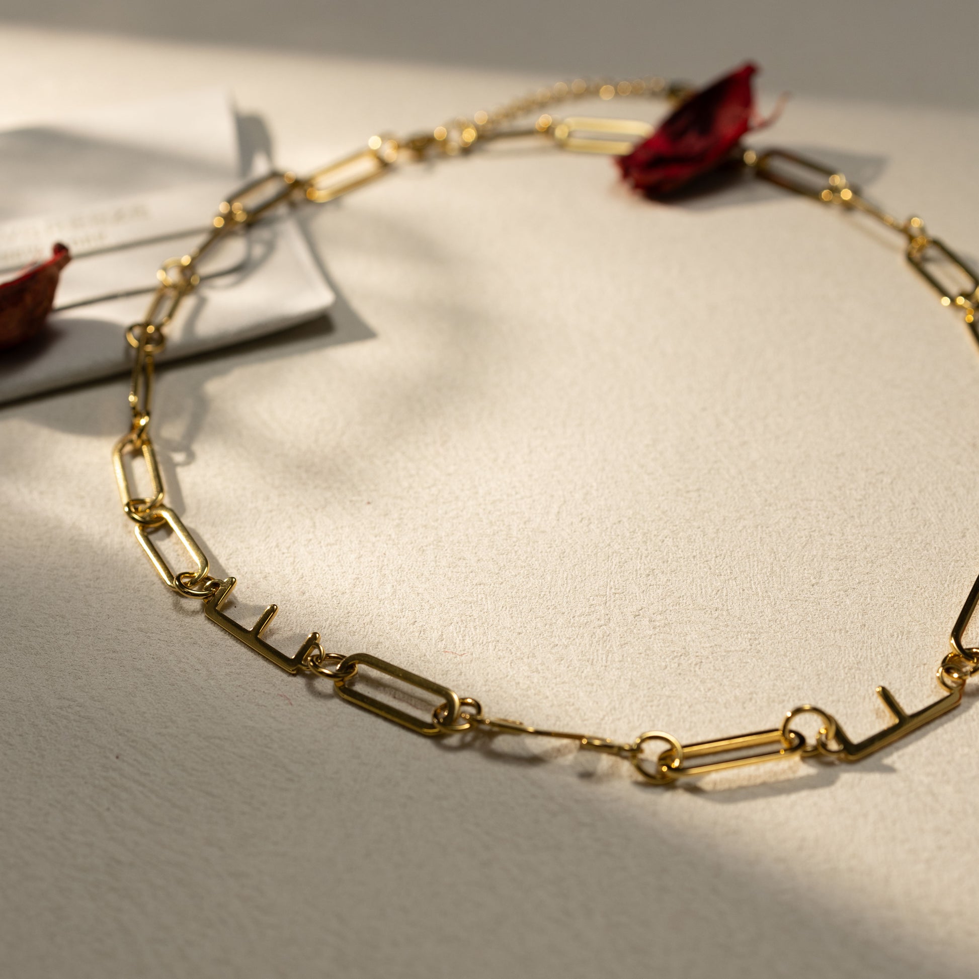 Flat lay of the Silvbreeze 18k gold paperclip chain necklace in warm natural light, featuring a durable 18K gold PVD finish and water resistant design.