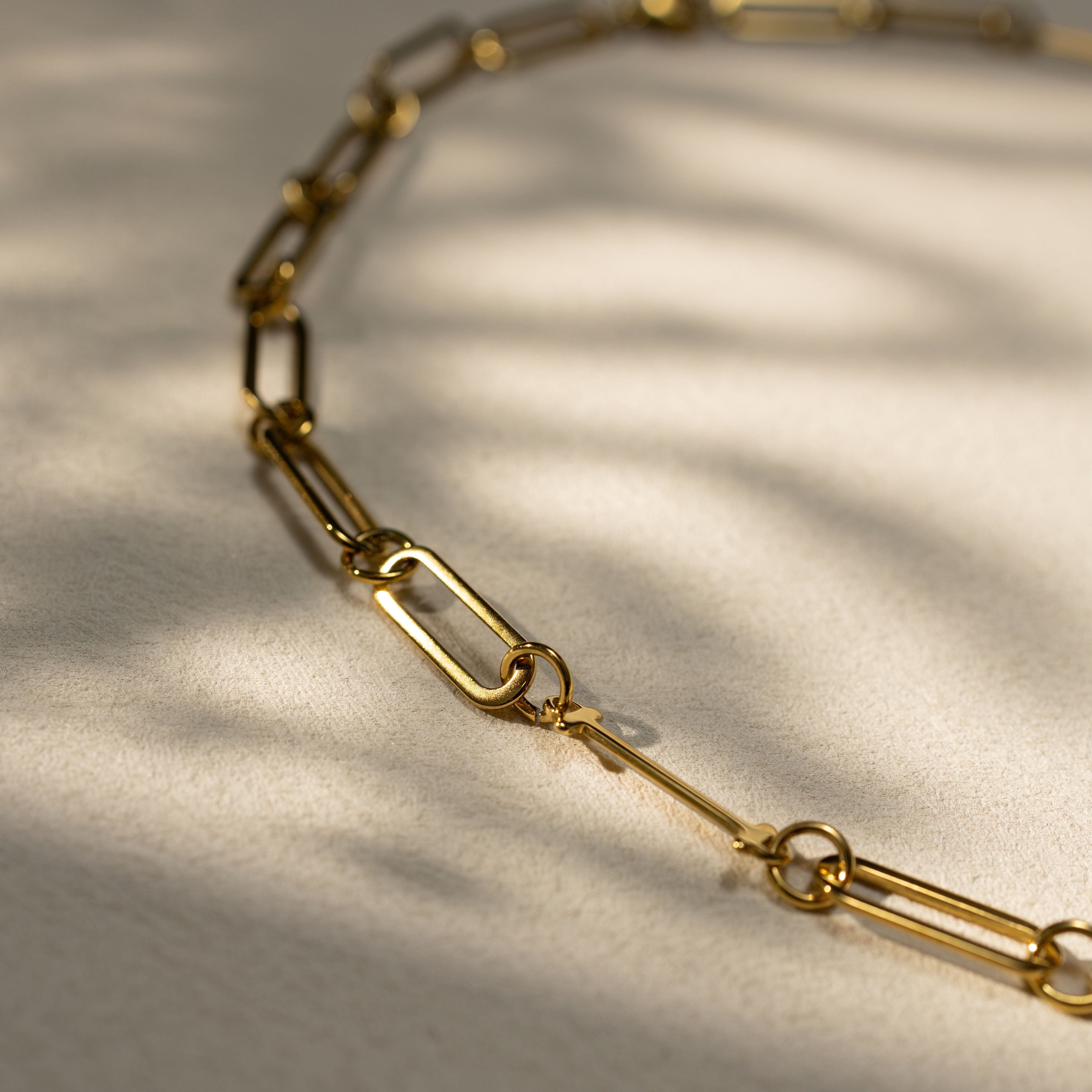 Closeup detail of Silvbreeze 18K gold MBTI personality necklace on a paperclip chain, showing premium finish and soft warm shadows.
