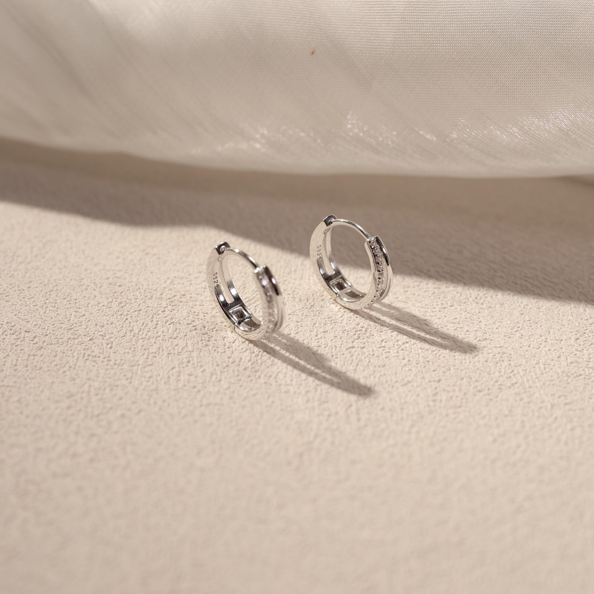 Nira white gold vermeil huggie earrings with cubic zirconia detail, sterling silver small hoop earrings lifestyle shot by SILVBREEZE