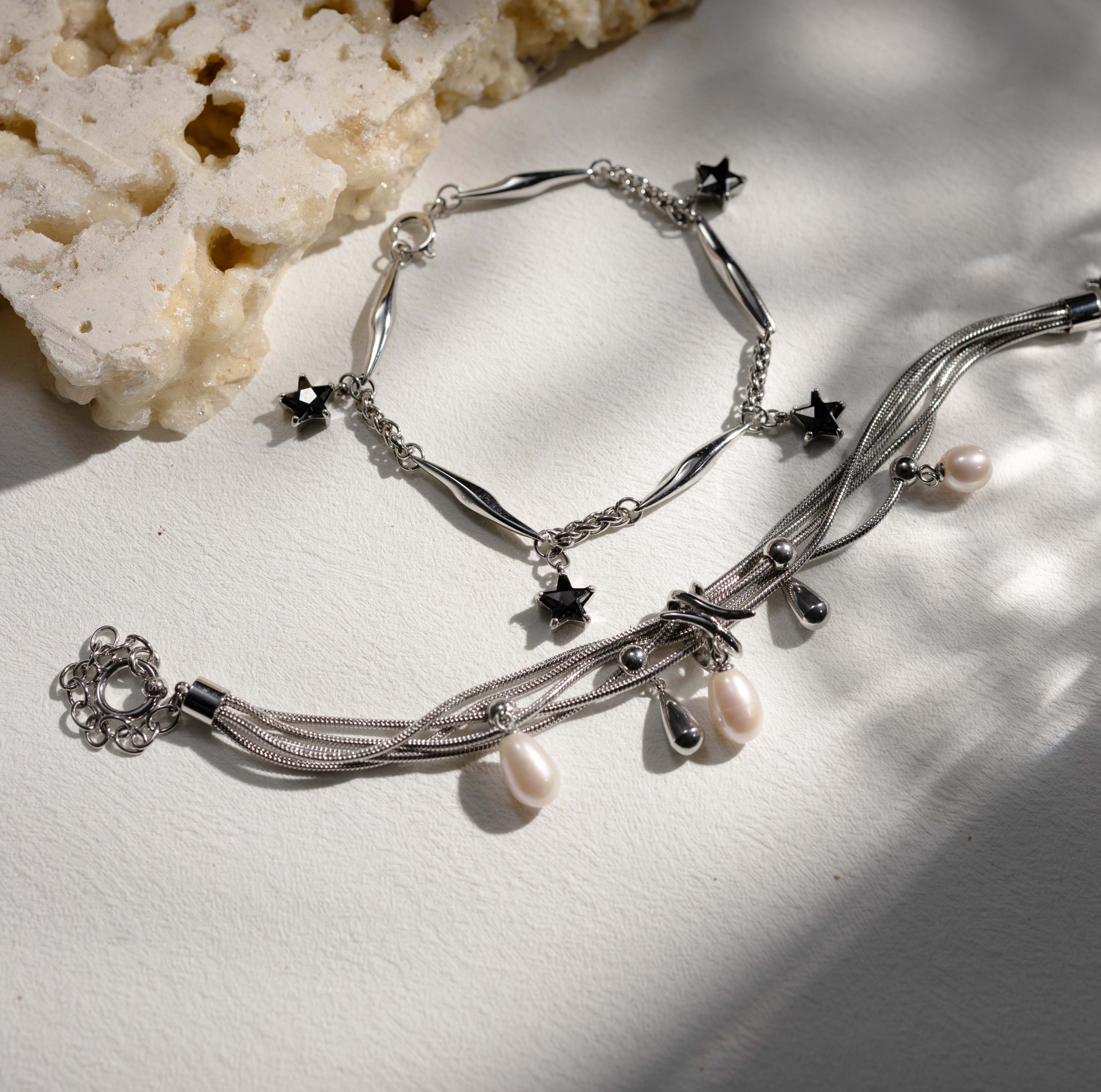 Silvbreeze NORN pearl bracelet styled together with a lightning charm bracelet in a layered jewelry scene