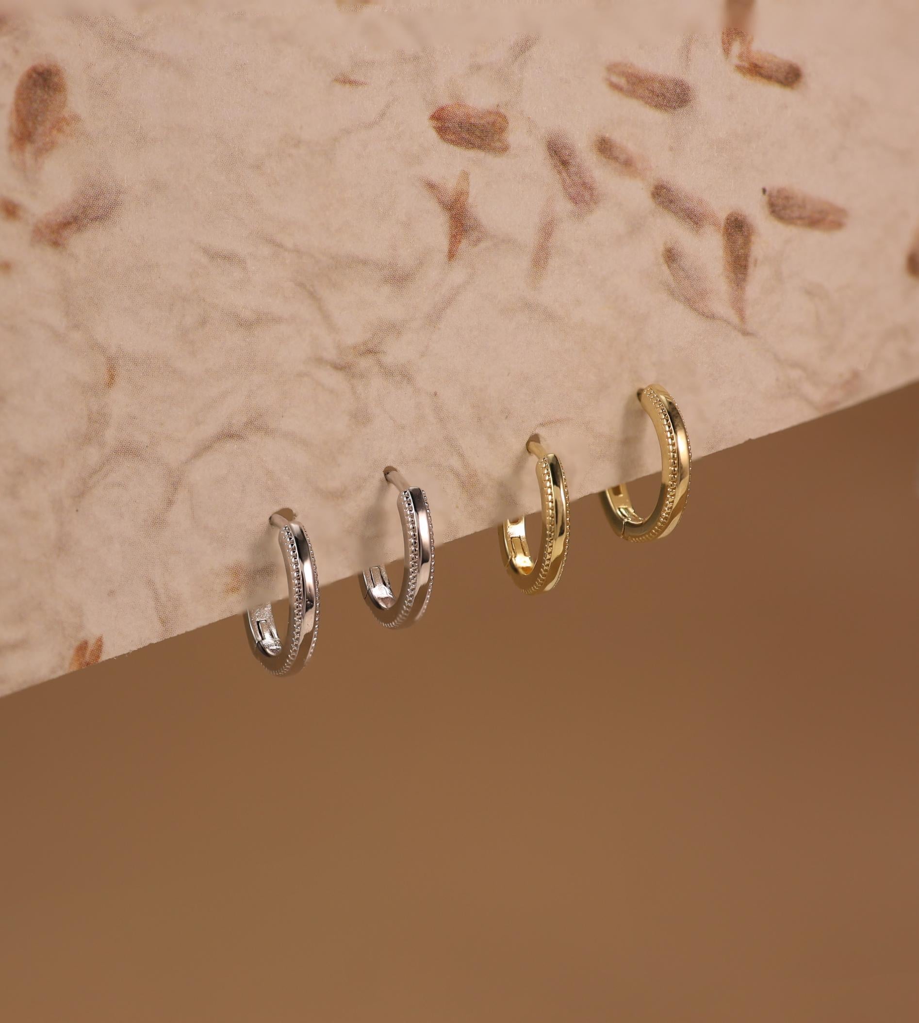 Onita sterling silver and gold vermeil huggie earrings vertically displayed on textured paper background, elegant small hoops by SILVBREEZE