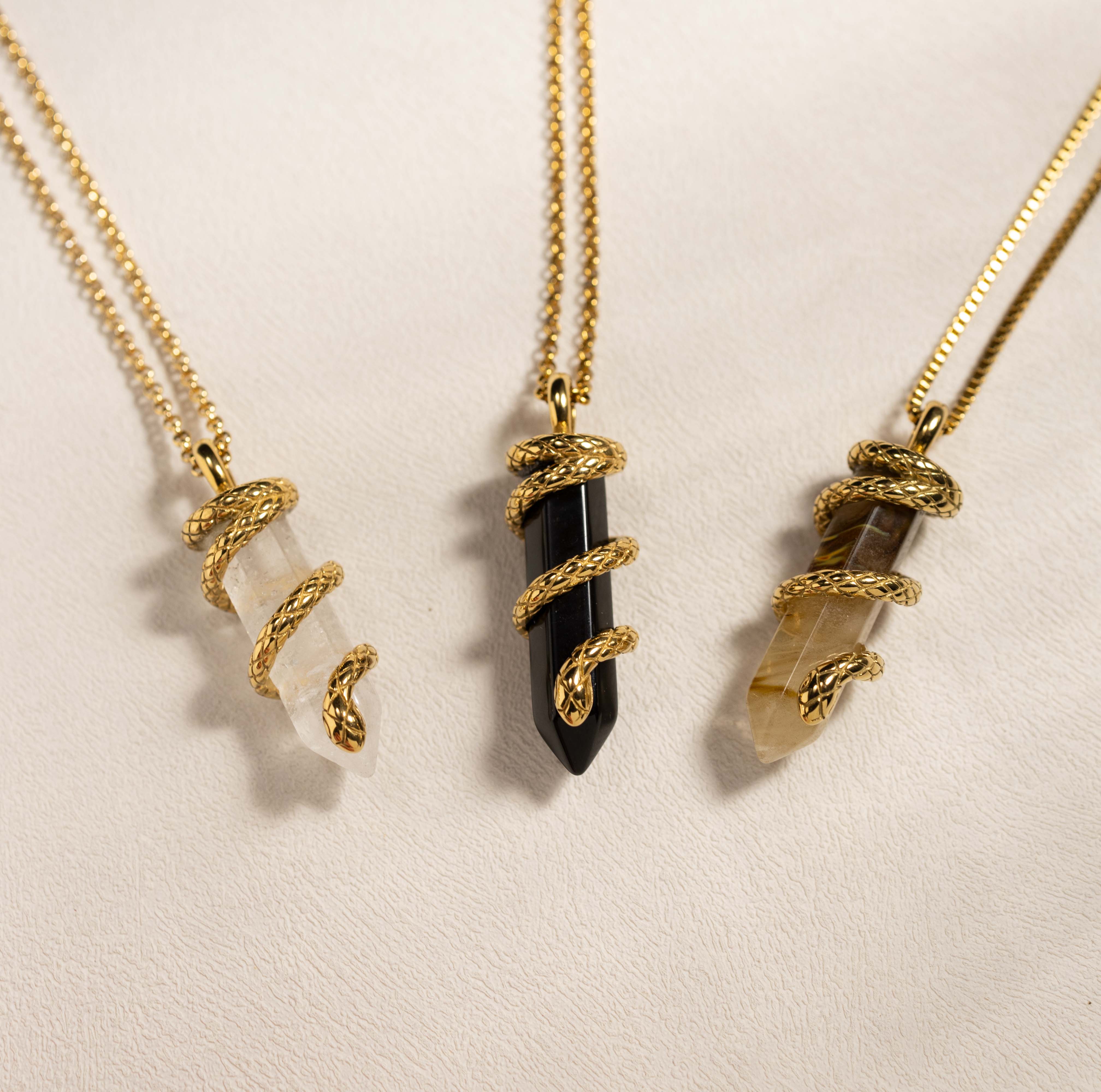 Silvbreeze Ouroboros serpent gemstone necklaces featuring obsidian, clear quartz, and tiger eye displayed together