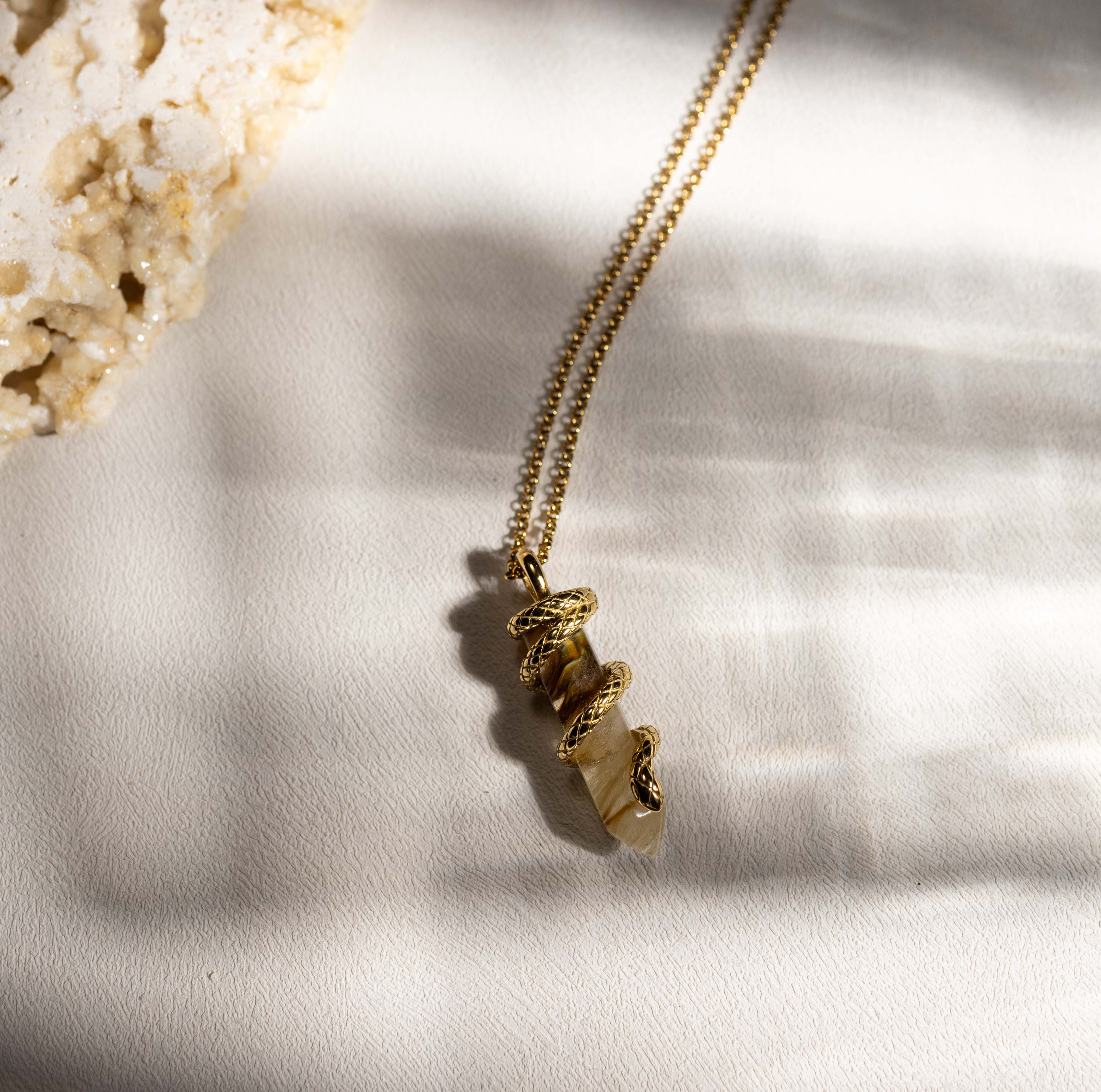 Silvbreeze Ouroboros serpent gemstone necklace featuring refined tiger’s eye, photographed in soft natural light to highlight the coiled serpent detail