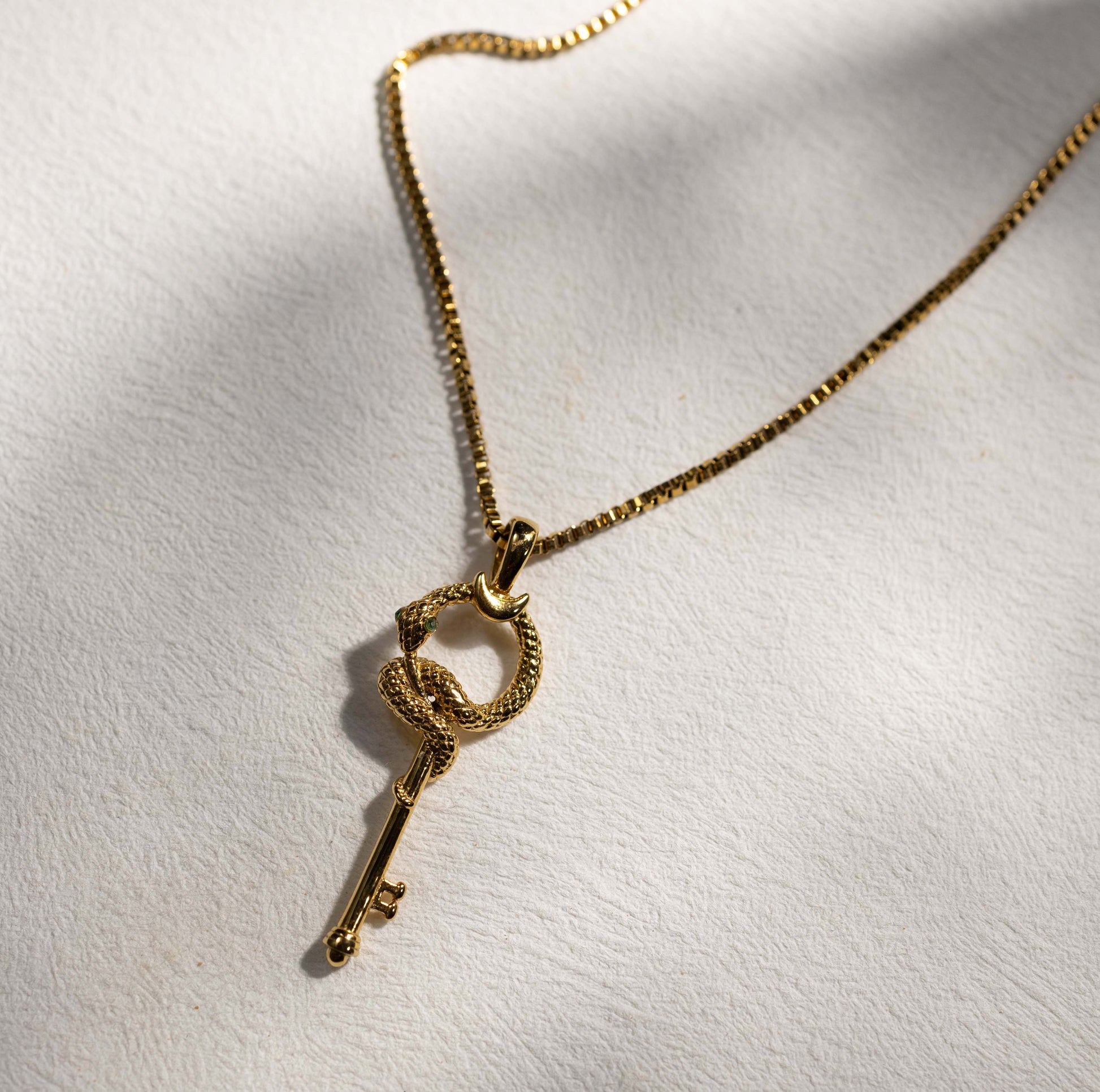 Silvbreeze gold serpent key necklace styled in natural light, highlighting the coiled snake and key pendant design
