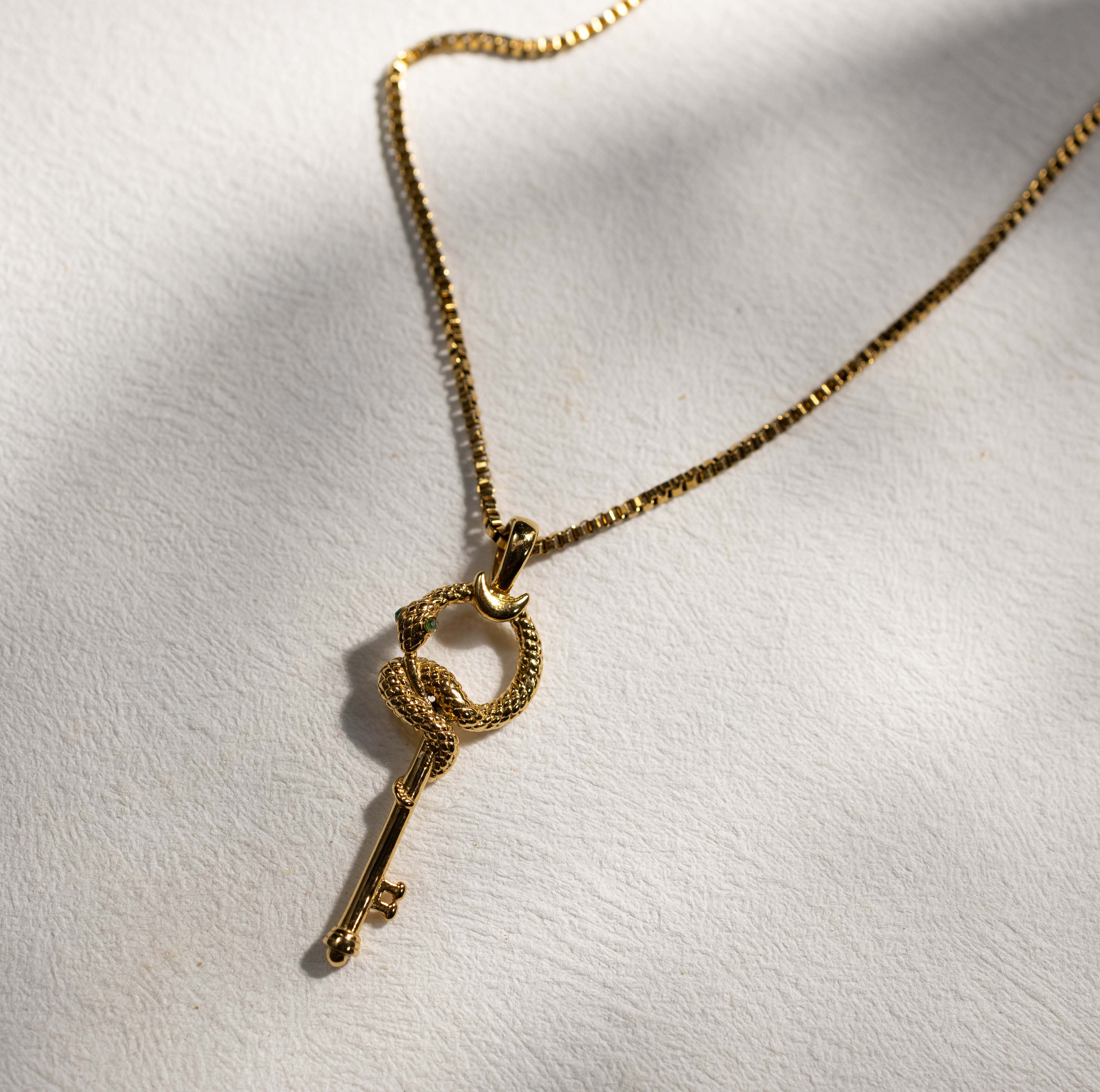 Silvbreeze gold serpent key necklace styled in natural light, highlighting the coiled snake and key pendant design