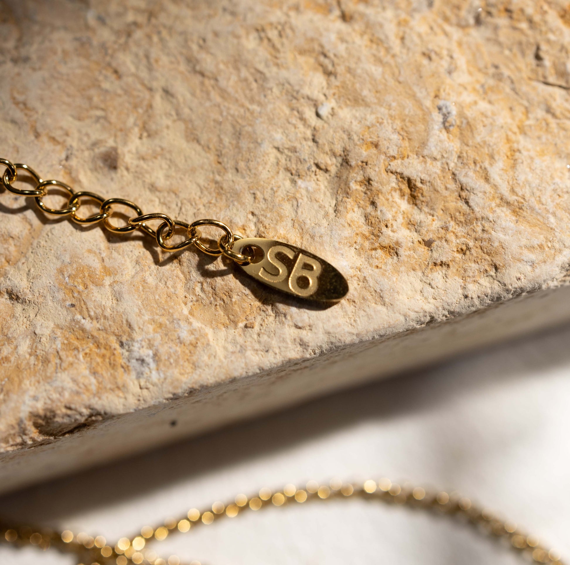 Detail of Silvbreeze gold snake key necklace showing the chain end and subtle brand letter charm