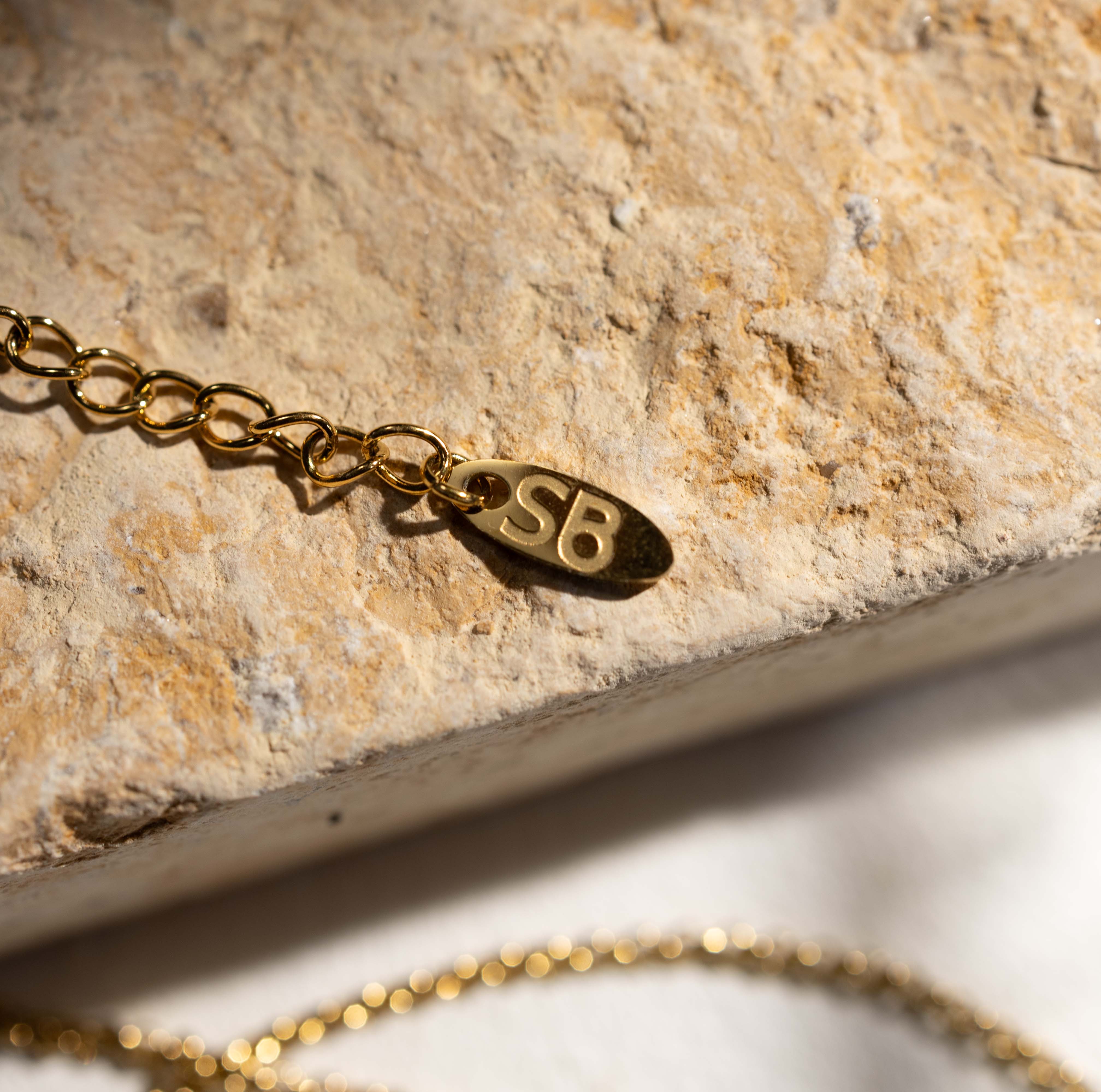 Detail of Silvbreeze gold snake key necklace showing the chain end and subtle brand letter charm